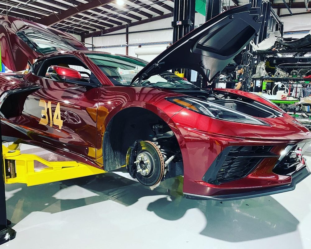 Dark red C8 Corvette with hood open on a lift