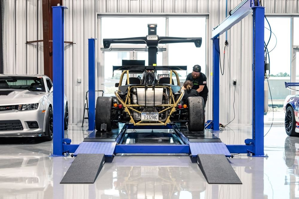 Ariel Atom-style kit car on the alignment rack with two technicians