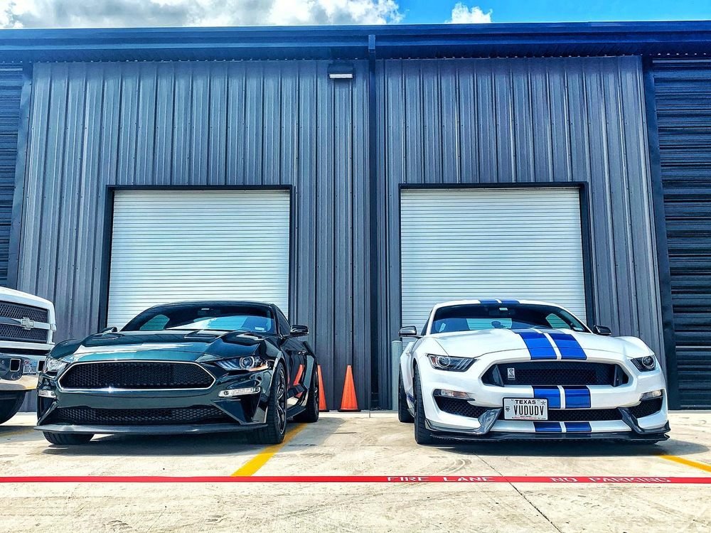 Black Mustang GT and white Shelby GT350 parked outside the shop