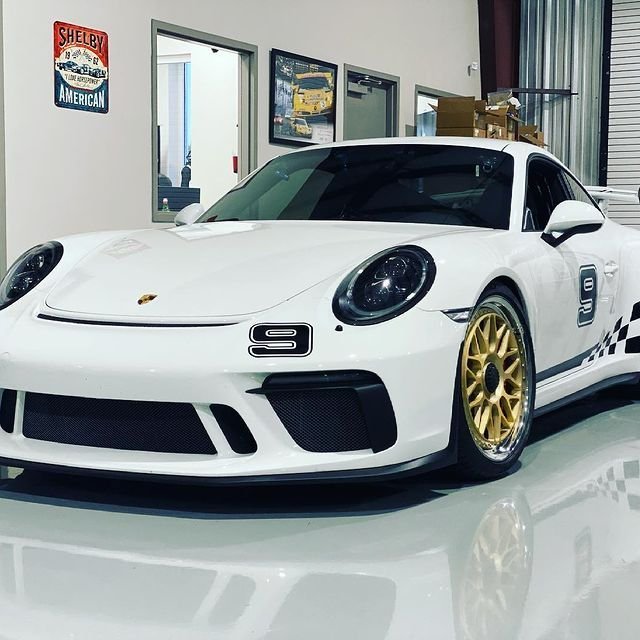 White Porsche GT3 Cup car with gold wheels in the showroom