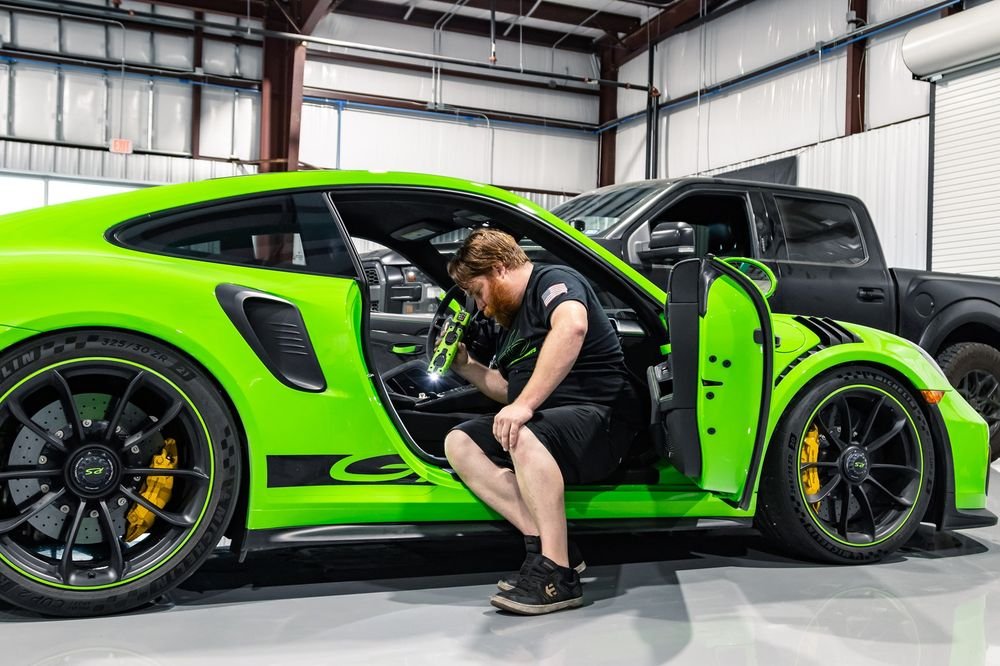 HD Motorsports technician finishing up work in a green Porsche GT3 RS