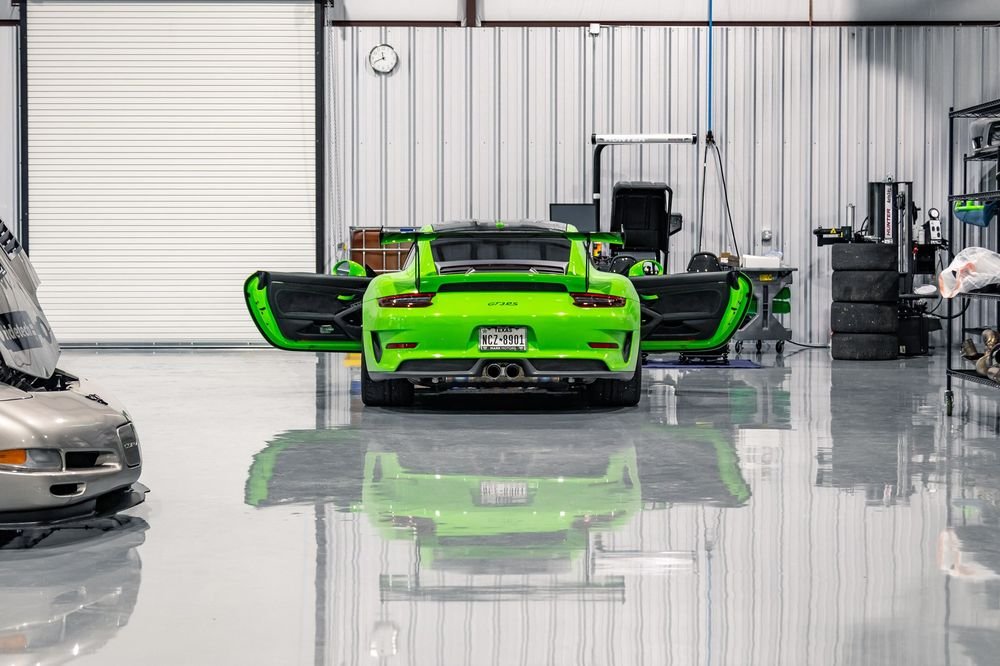 Rear view of a green Porsche 991 GT3 RS with doors open in the shop