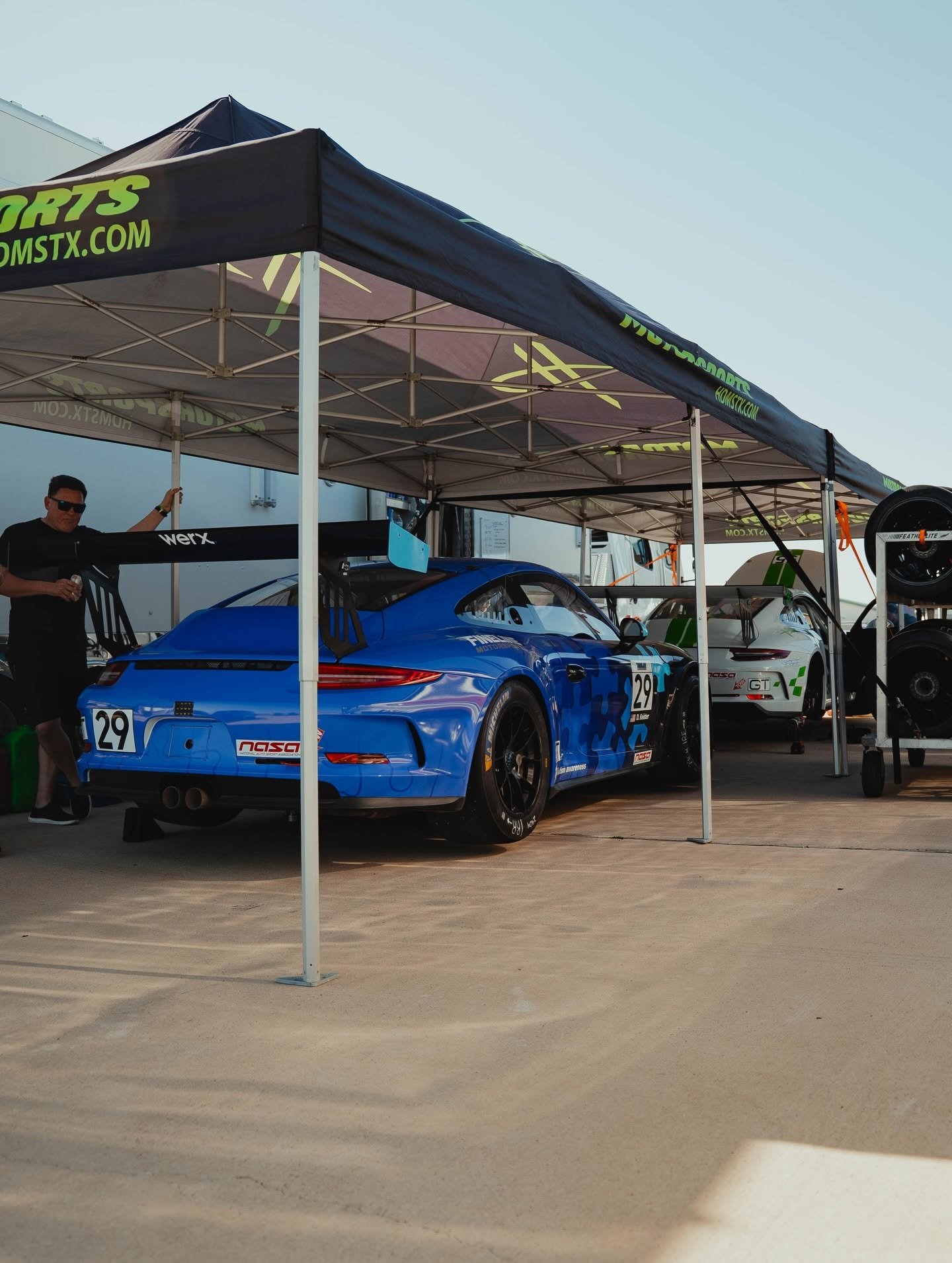 HD Motorsports branded paddock tent with a blue Porsche GT3 Cup race car